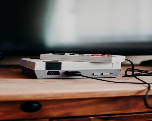 Modern gaming console and controller resting on a display table